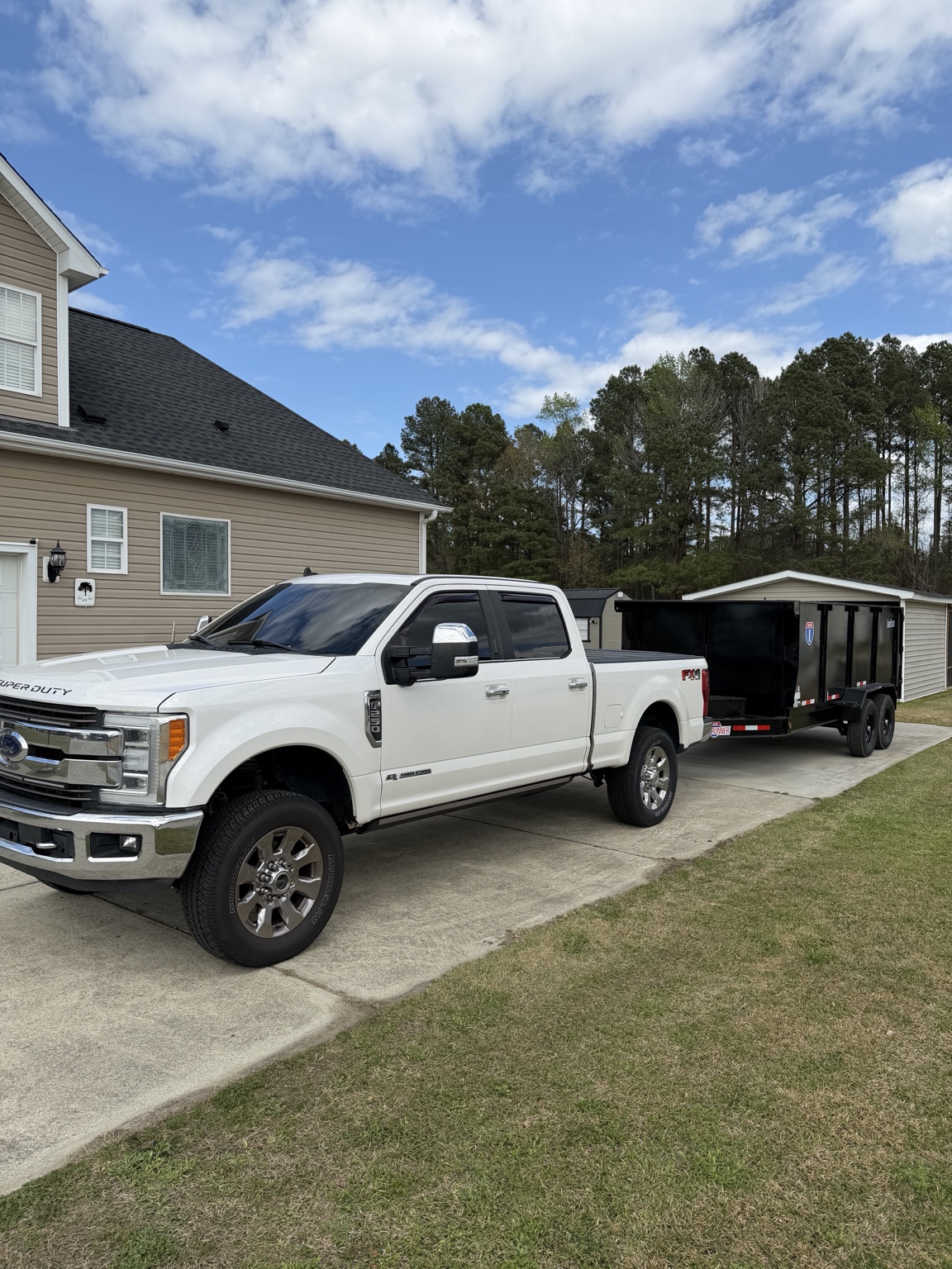 White Ford truck towing black dump trailer